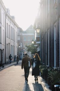a man and woman walking down a sidewalk between buildings