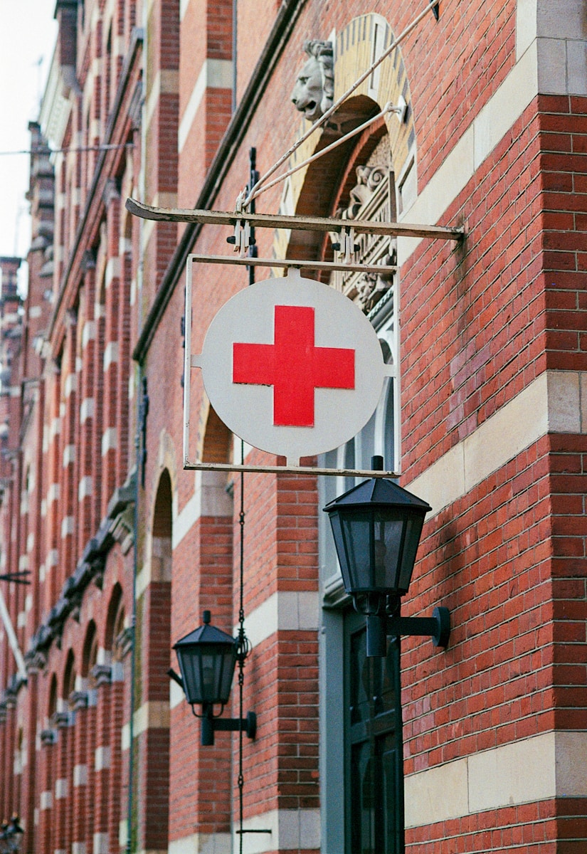 a red cross sign hanging from the side of a building