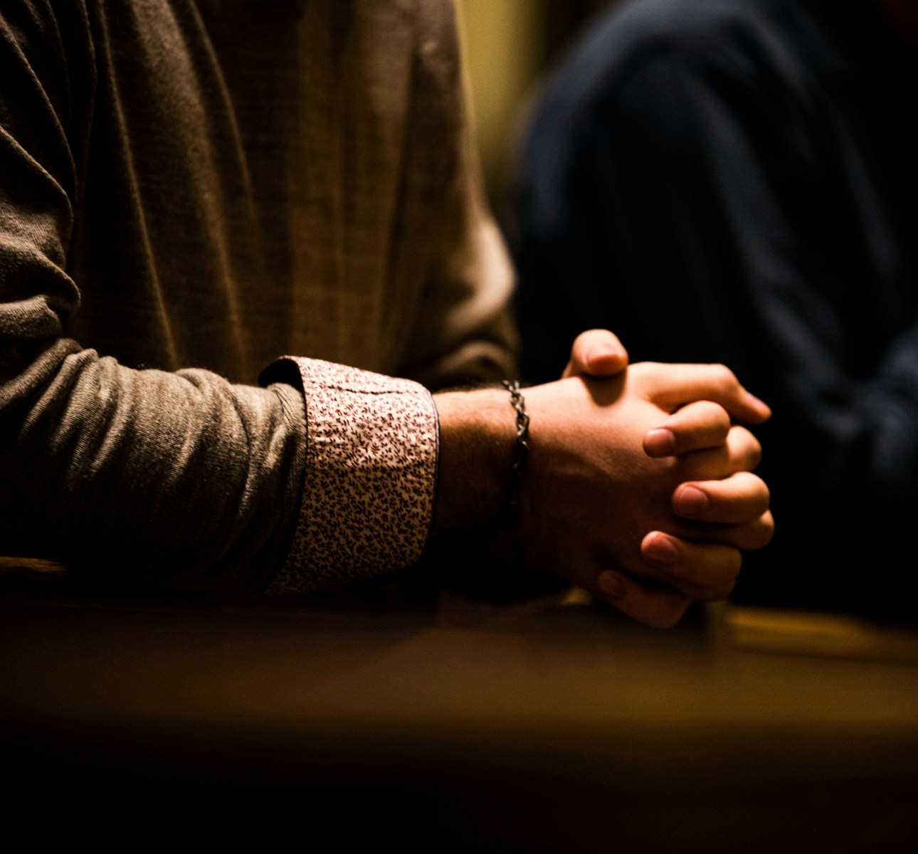 two people holding hands while sitting at a table