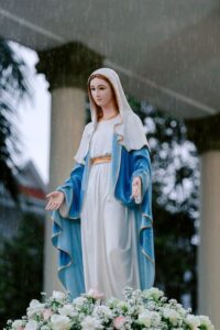 Serene statue of the Virgin Mary with a blue and white robe in a peaceful garden.