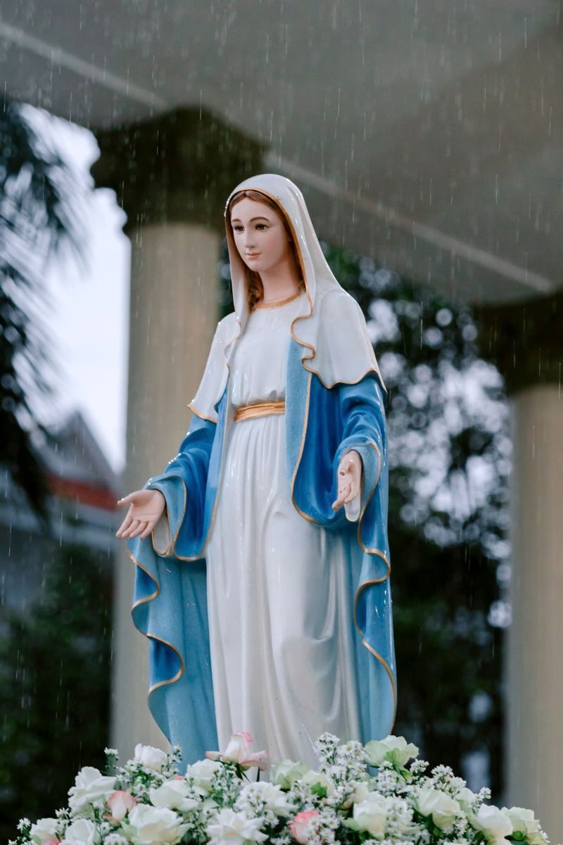 Serene statue of the Virgin Mary with a blue and white robe in a peaceful garden.